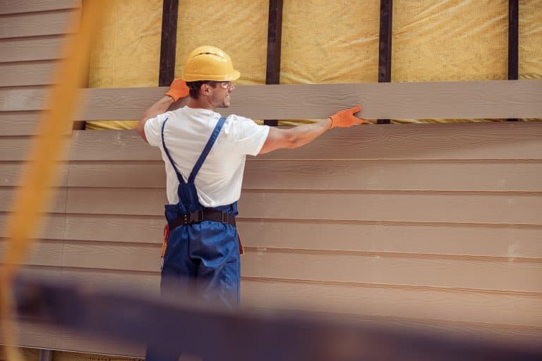 Smiling male worker building cabin at construction site